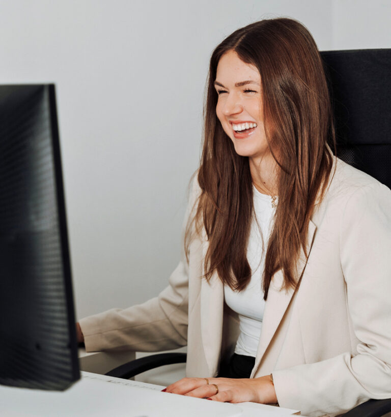 Junge Frau sitzt am Schreibtisch und freut sich über die CadiaOffice Warenwirtschaftssystem-Lösung für Deutschland