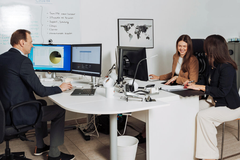 Ein Mann und zwei Frauen arbeiten im Büro mit der CadiaOffice Warenwirtschaft für Schweizer Unternehmen